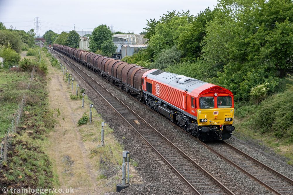 a red railway locomotive is seen hauling some burgundy covered steel wagons 