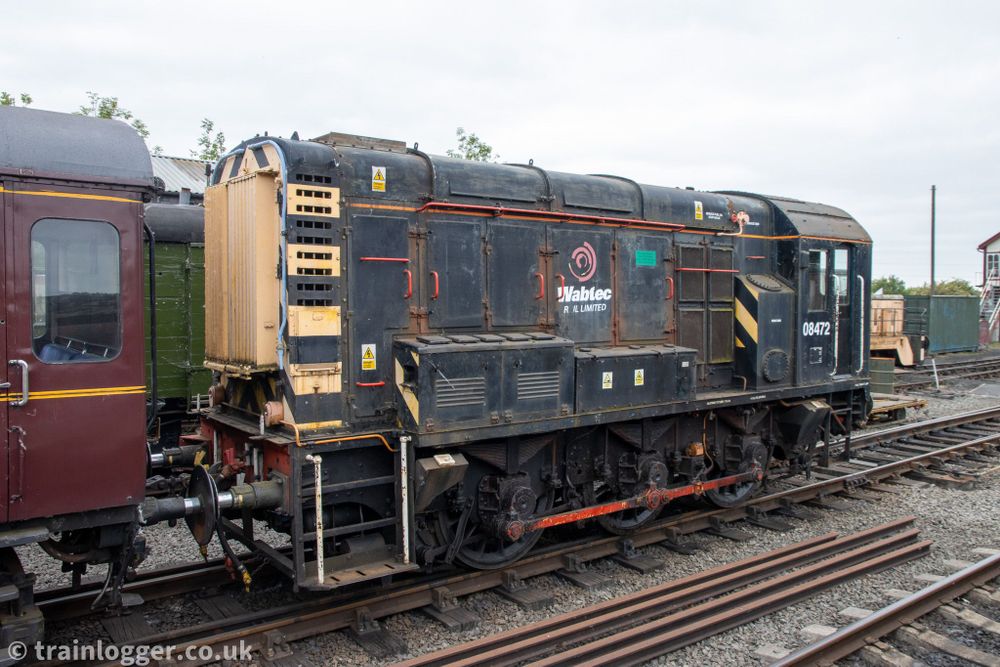 a small black locomotive  is seen parked in a siding