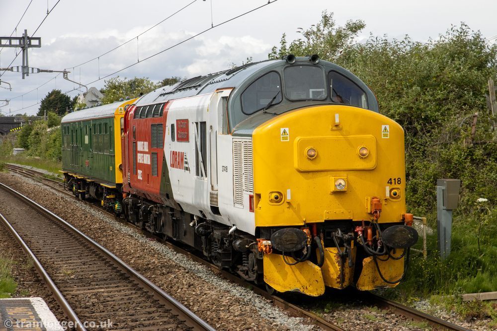 a smart white, red, grey and yellow locomotive is seen hauling a green carriage