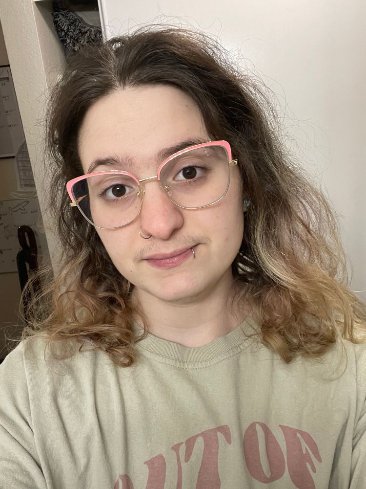 cable wearing cat eye glasses with a thin metal frame on the bottom and thicker pink on the top