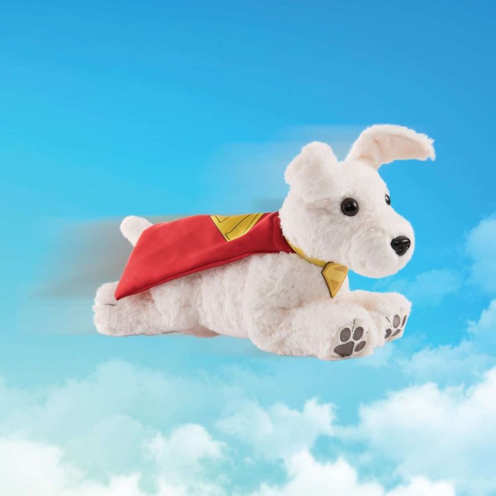 Image of a plushie of Krypto the SuperDog from the Superman movie.  A white terrier in a red cape, flying against the backdrop of a partially cloudy sky.
