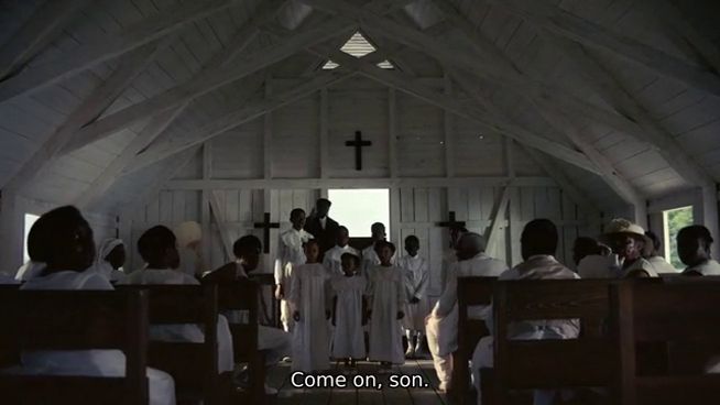 Screenshot of the film, showing a Black congregation in a small white wooden church, all dressed in white except the preacher at the front in black.

Caption reads: "Come on, son."
