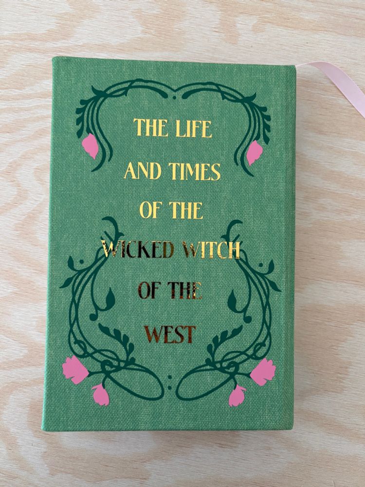 A hardcover handmade special edition of the book Wicked by Gregory Macguire. Made from green cloth with green leaf and pink flower details and gold foil lettering. 