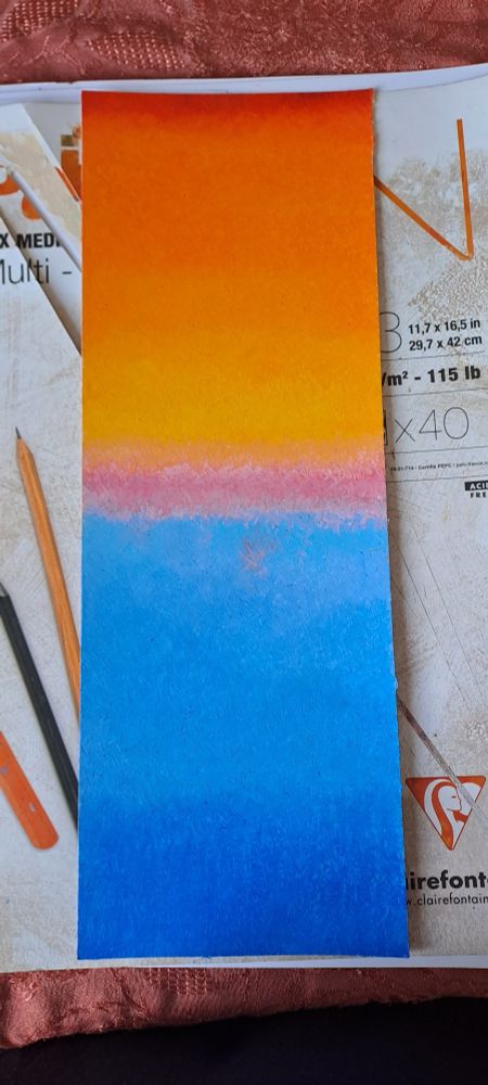 Coucher de soleil avec des couleurs bleues et orangées.  Pastel à l huile format 14,7x42cm.