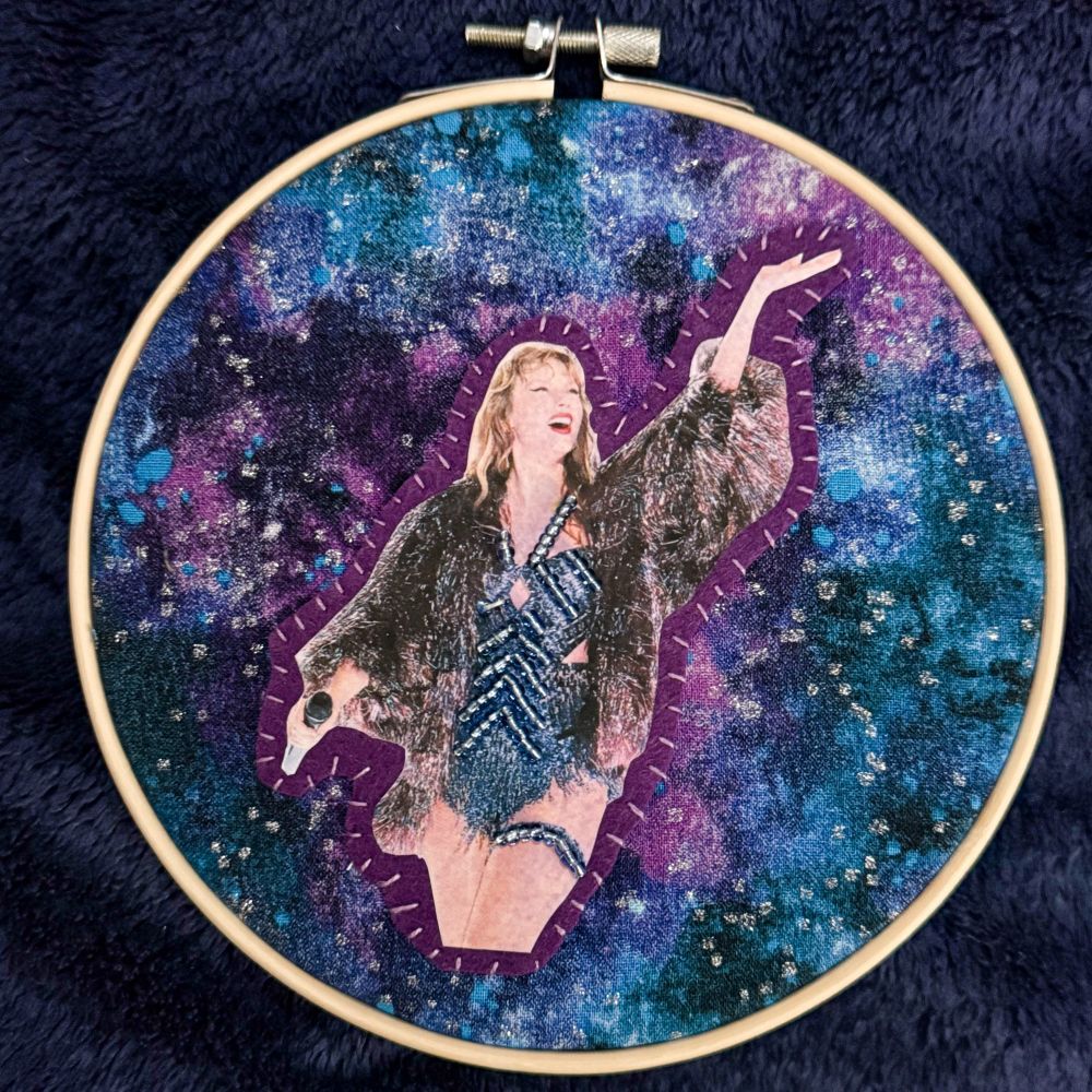 a taylor swift beaded embroidery on a space themed fabric 