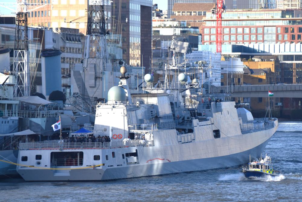 New Indian Navy Frigate INS TUSHIL moored alongside HMS Belfast (1938) in the Pool of London on the River Thames during a stop-off on it's delivery voyage to India - the view is from the rear 3/4 and a Police launch is passing by