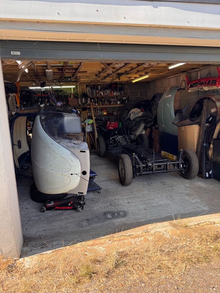 A garage containing a VW beetle split into two halves with the body shell on its side