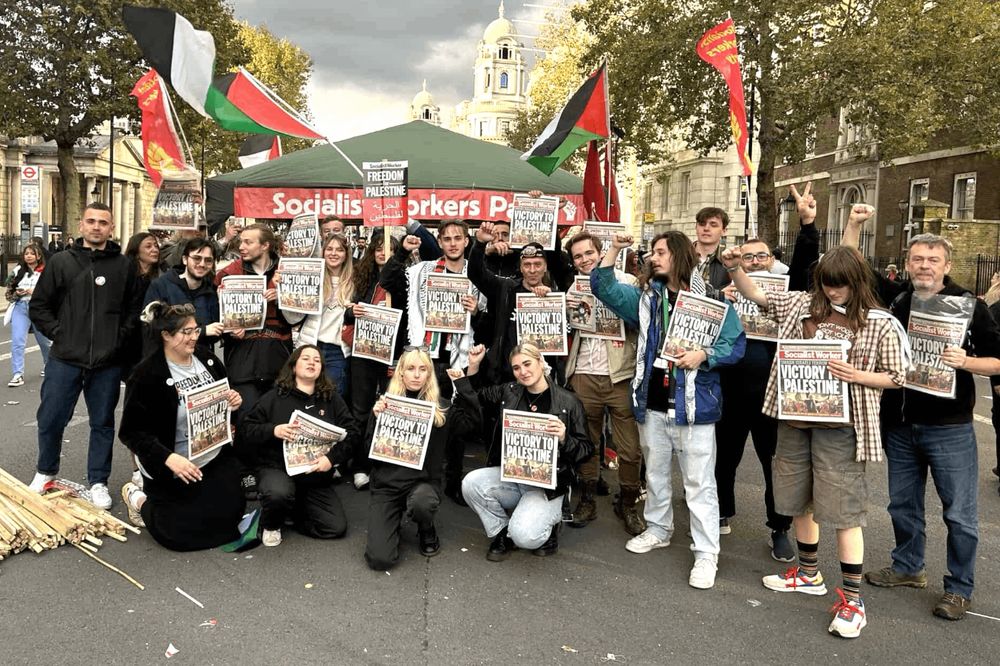 Socialist Workers Party campaigners, many with fists raised in classic gesture of rebellious defiance, holding up front page of Socialist Worker newspaper at demonstration in London.