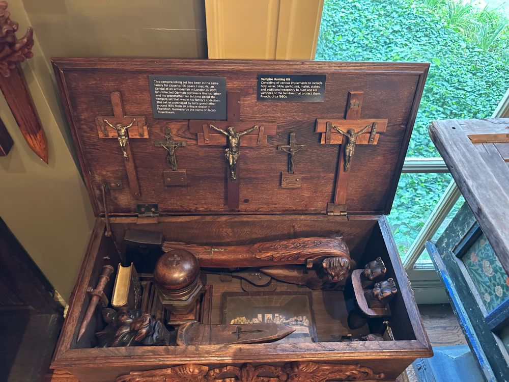 This is a photo of an antique wooden trunk, likely from the 1860s, full of various implements for killing vampires, including stakes, a mallet, holy water, garlic, and a bible.