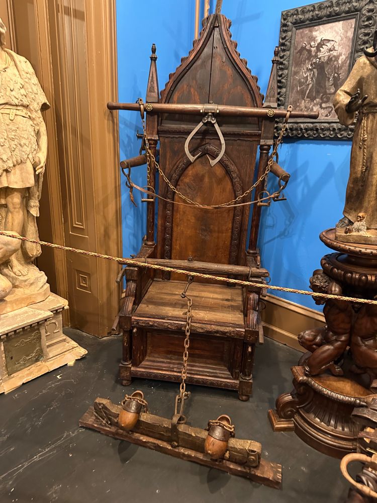 Not sure if this is an exorcism chair or a torture device because it is horrifying!! There is a bar with what appear to be enormous metal pincers for the head, plus a chain attached to some kind of awful looking feet restraints 
