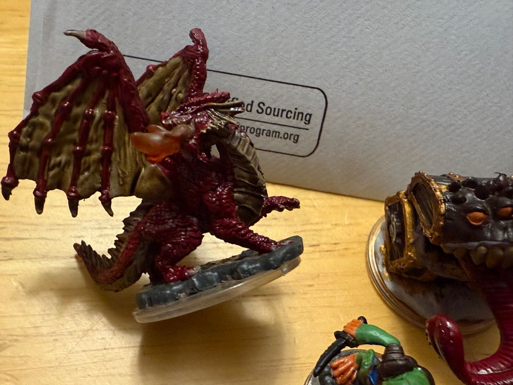 Closeup of ared dragon wyrmling miniature, painted and washed. 