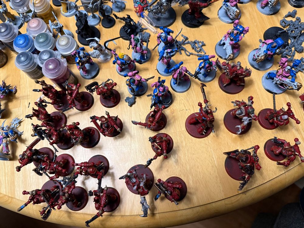 A broader picture of a kitchen table with models in various states of painting.  