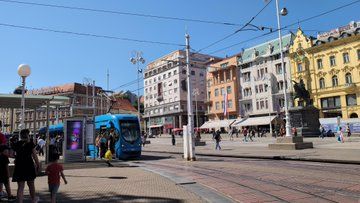 Tram at stop with classic European style buildings in the background 