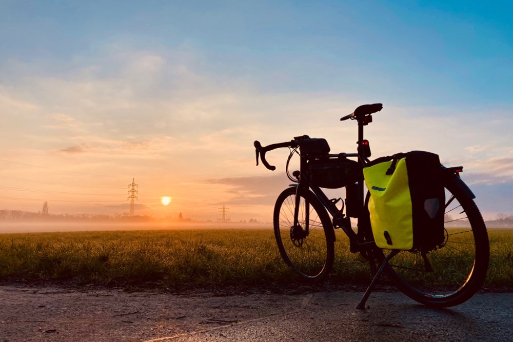 Ein blauer Himmel, Wolkenschleier, Sonnenaufgang über dem Feld mit Nebel. Mein Bulls Gravelbike auf der rechten Seite Richtung Sonne. Wunderschön.