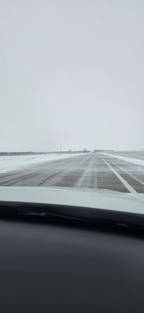 Picture of snowy one lane highway with ice and snow drifting over it in Minnesota