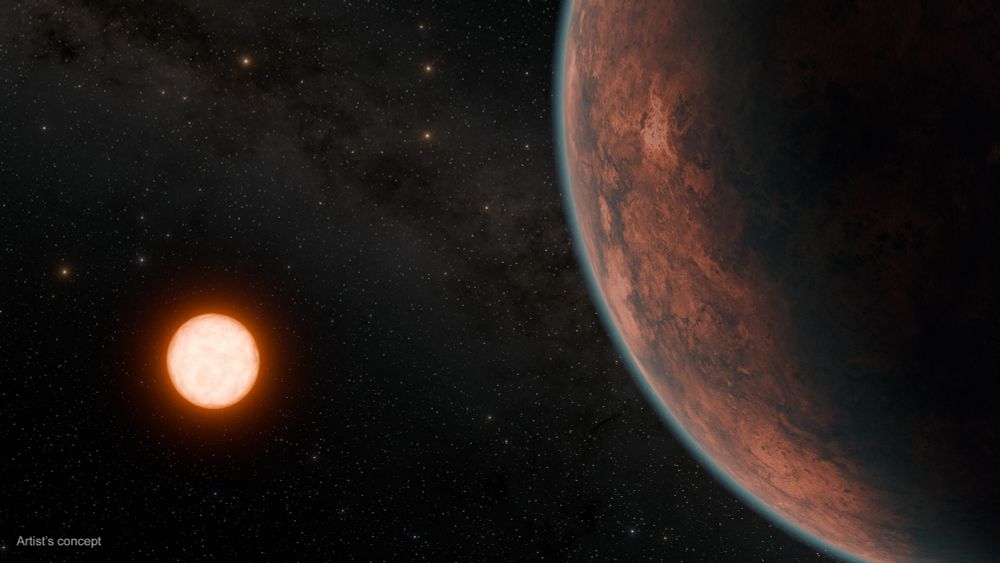Red planet at the right of the frame illuminated by a reddish host star, with a distant starfield in the background.