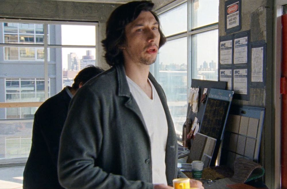 Adam Driver as Randy in the Meyerowitz Stories, holding a tiny yellow espresso cup