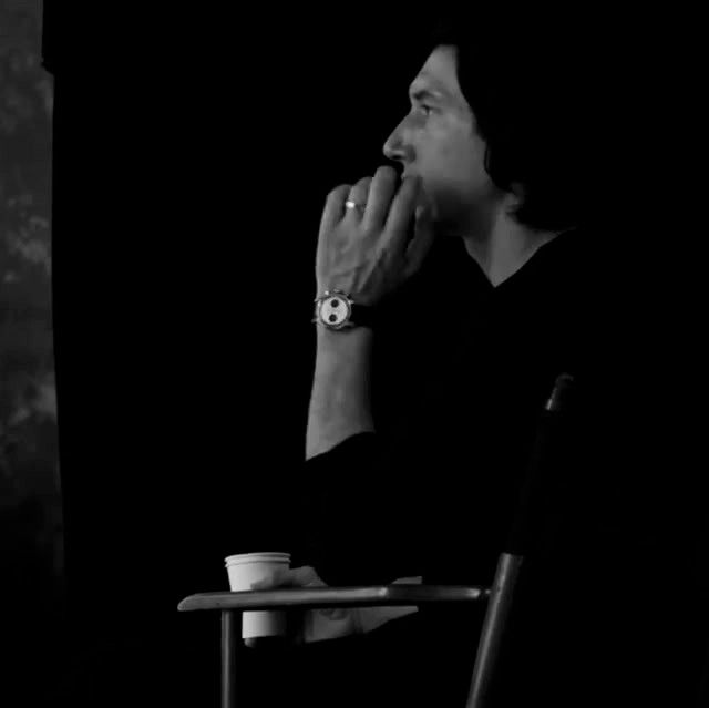 Adam Driver looking pensive with a coffee cup behind the scenes of his Breitling photoshoot 