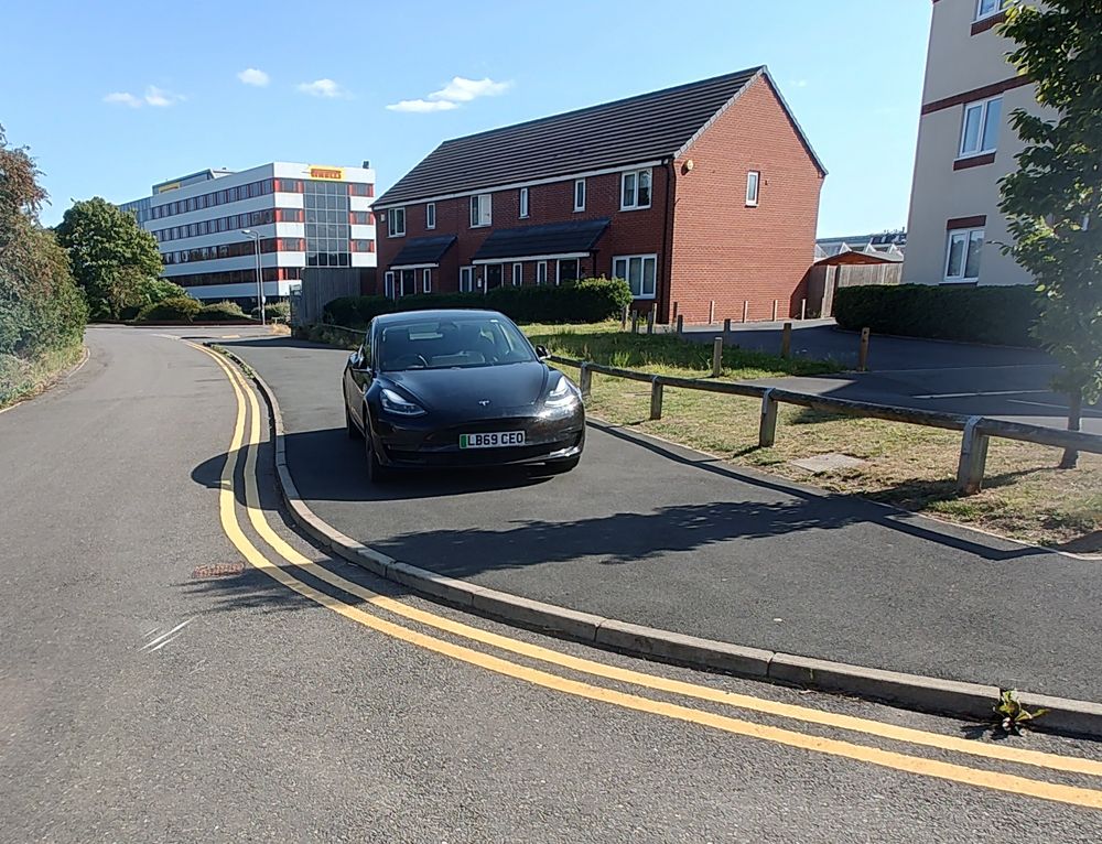 A Tesla parked fully on the pavement next to double yellow lines, reg LB69CEO