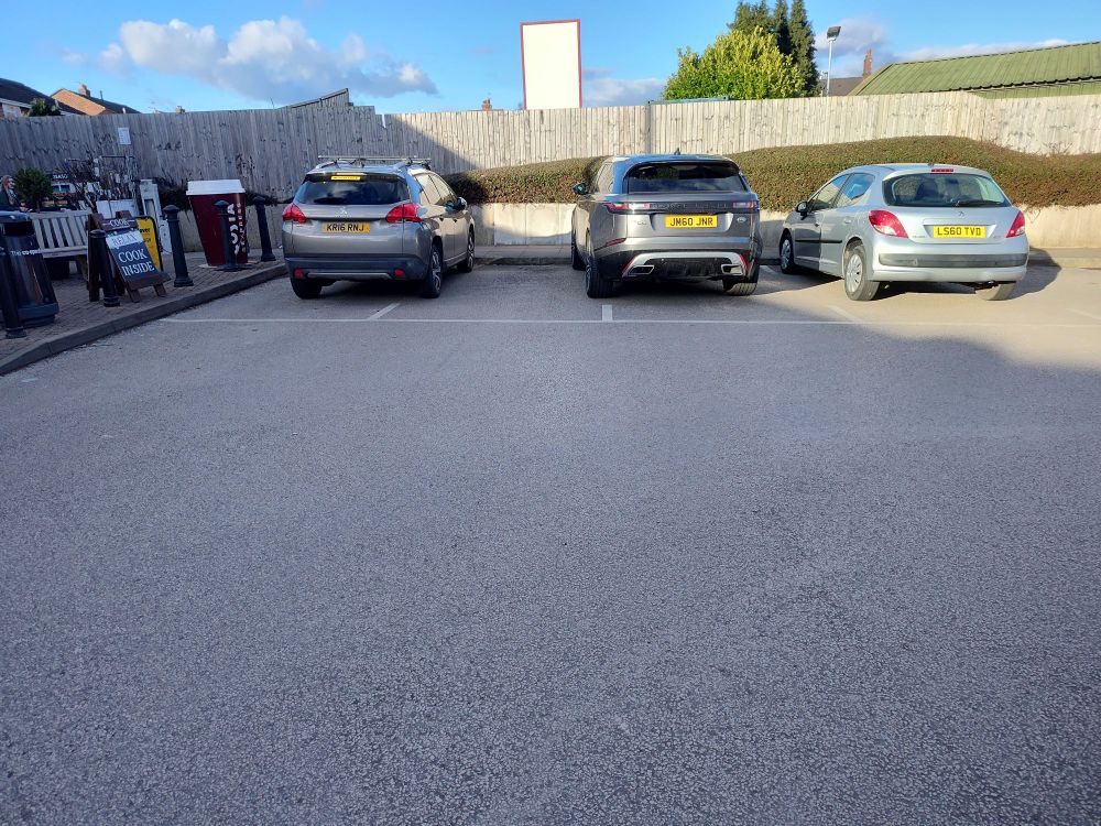 Two SUVs parked, both part-way outside of their respective parking spaces