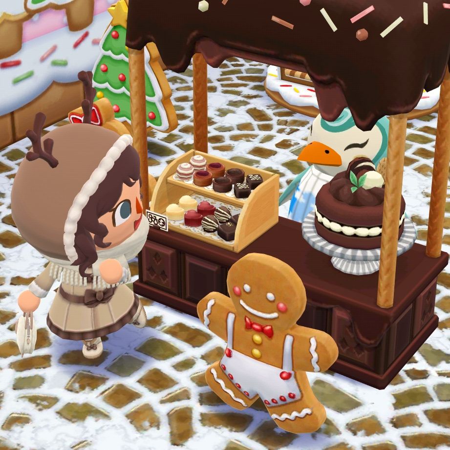 My ACPC character striking a cute pose next to a chocolate stall with assorted bonbons and a big chocolate cake. There is a gingerbread man with overalls in front of the stand. Sprinkles the penguin is behind the stand. 
