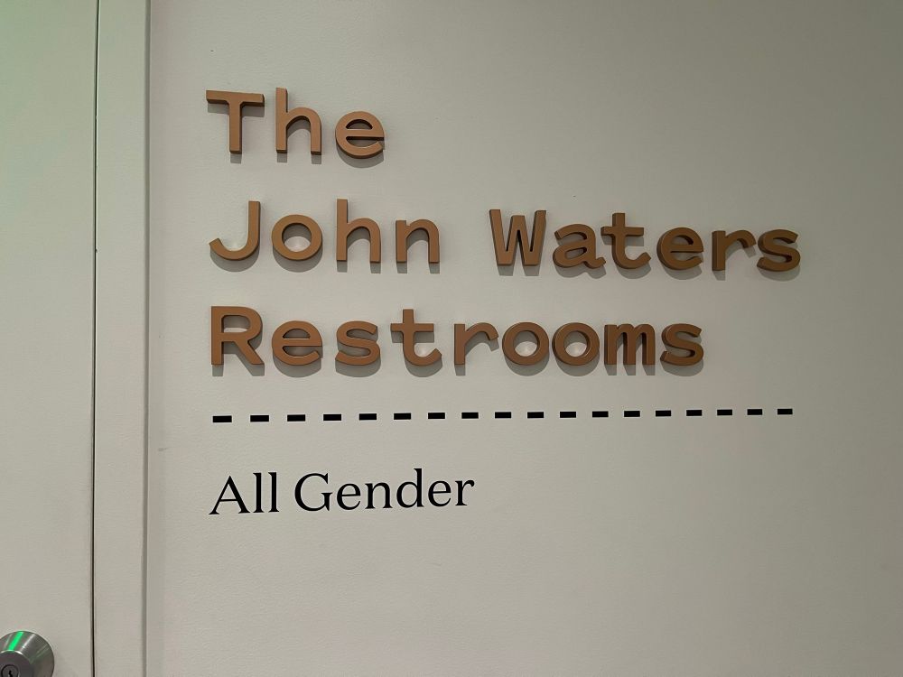 Photo of the all-gender restroom entrance at the Baltimore Museum of Art, named for benefactor and patron of the arts John Waters. 