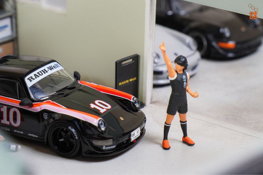 A man and Porsche RWB 964 Black, No.10 Thailand Special Edition by Tarmac Works in 1:64 scale with 1:64 figure on AREA 164