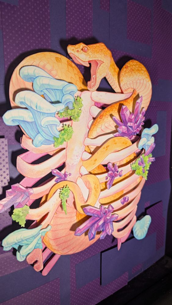 Complete cut paper and watercolor illustration of snake twined inside a ribcage with mushrooms and crystals. Seen at a side angle to show depth. 