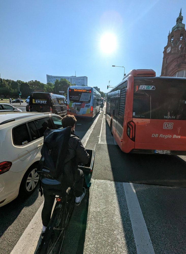 Radweg vor dem Hauptbahnhof in Wiesbaden, der von links und von rechts von Bussen befahren wird.