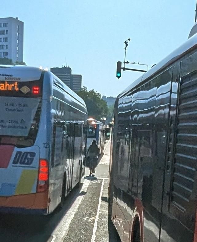 Radweg vor dem Hauptbahnhof in Wiesbaden, der von links und von rechts von Bussen befahren wird. In der Mitte ein Radfahrer.