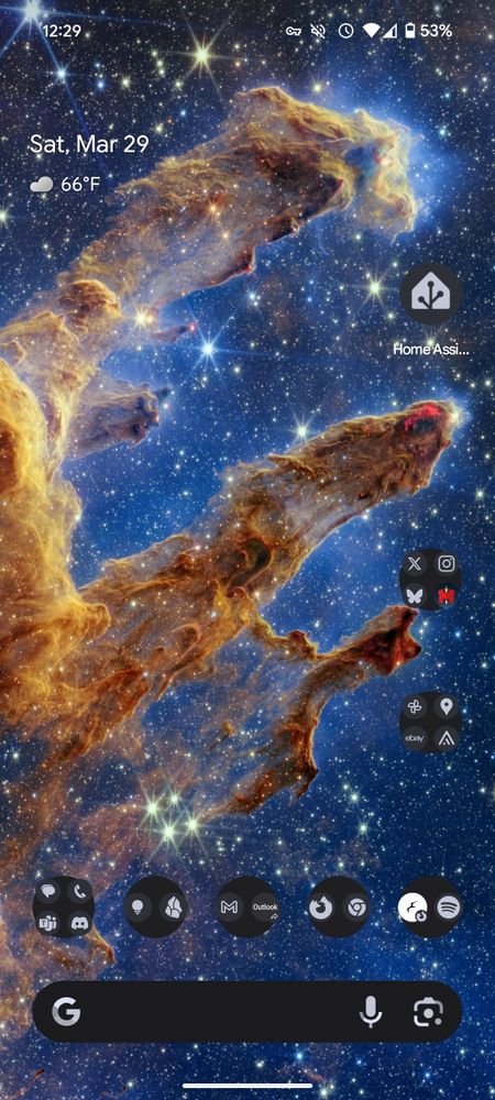 A screenshot of an Android home screen. The background is the Pillars of Creation taken by the James Webb Space Telescope. 

The home screen has various app icons, the date, weather, time, and a Google search bar that can't be removed from the stock Pixel launcher even if you never use it and would love the extra screen real estate. 