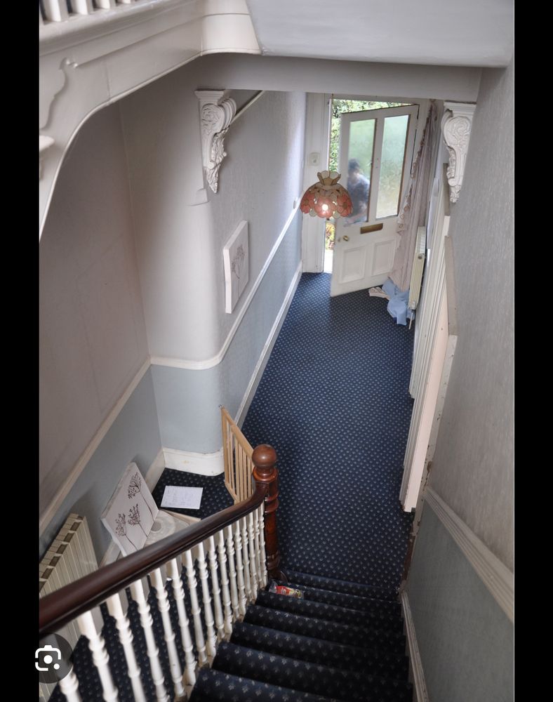 Victorian house with skinny corridor and skinny staircase. Carpeted, obviously.