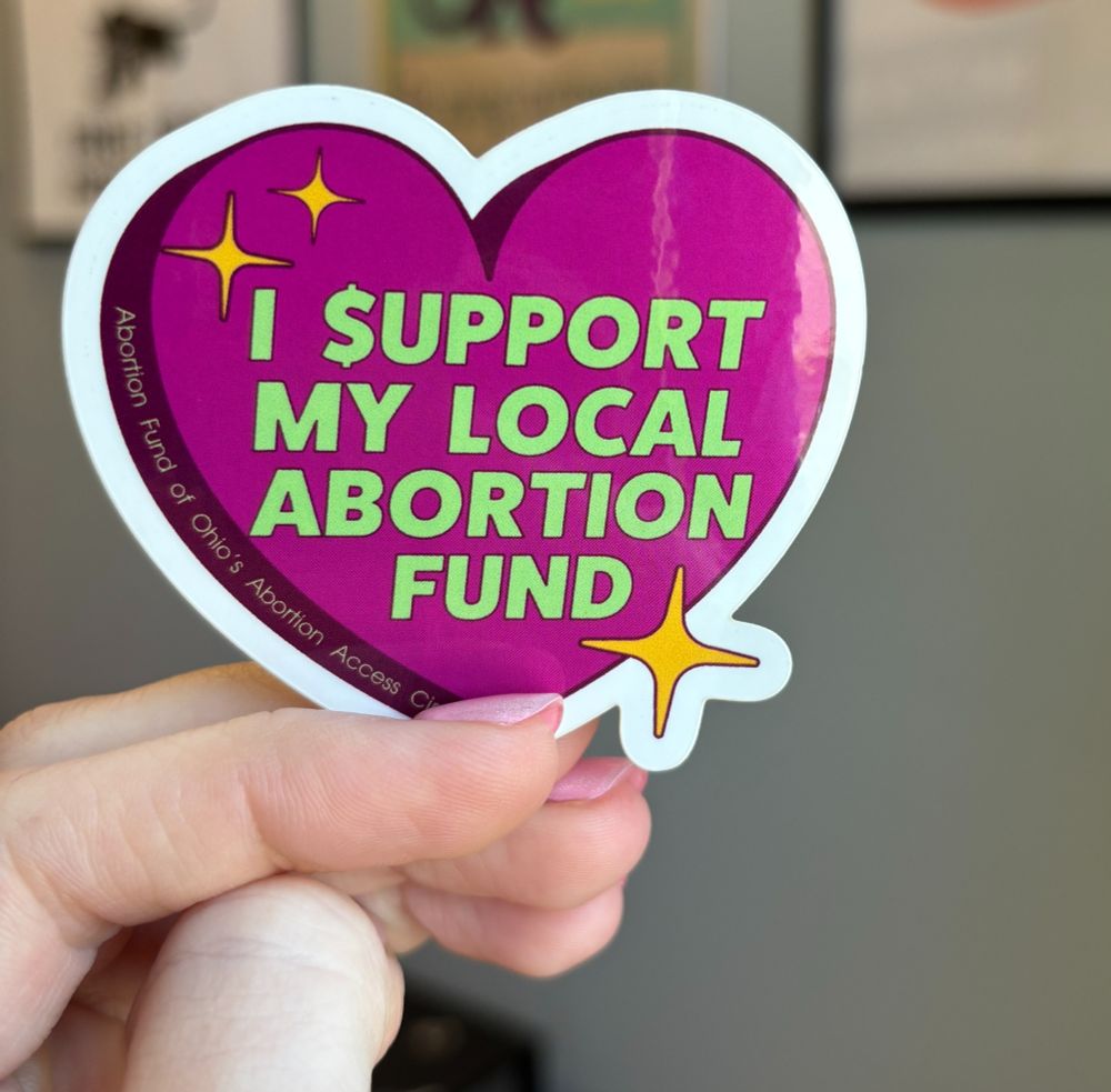 Pink and green heart sticker that reads, "I support my local abortion fund"