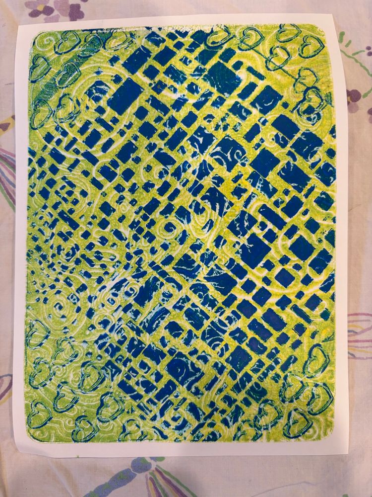 Gelli printed white rectangular paper with chartreuse background. Blue quadrangles and hearts are stenciled and stamped in the foreground.