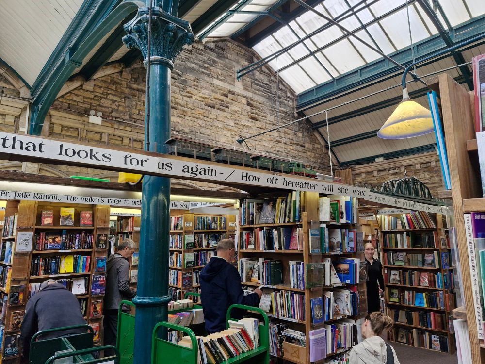 Bookshelves packed under a tall roof as a model train runs above customers' heads. 