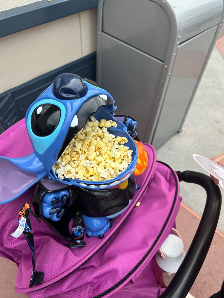 A plastic container shaped like a blue-colored individual from other space unhinging its jaw so it accommodate more than its fair share of popcorn. 