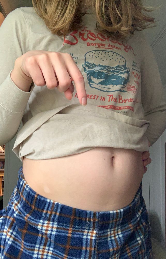 Sam, dressed in comfy-looking pajama bottoms and a casual shirt, looms over you. She's easily a head or two taller than you as she points downwards, her other hand on her hip. You can already feel her magic working as you dwindle down further...