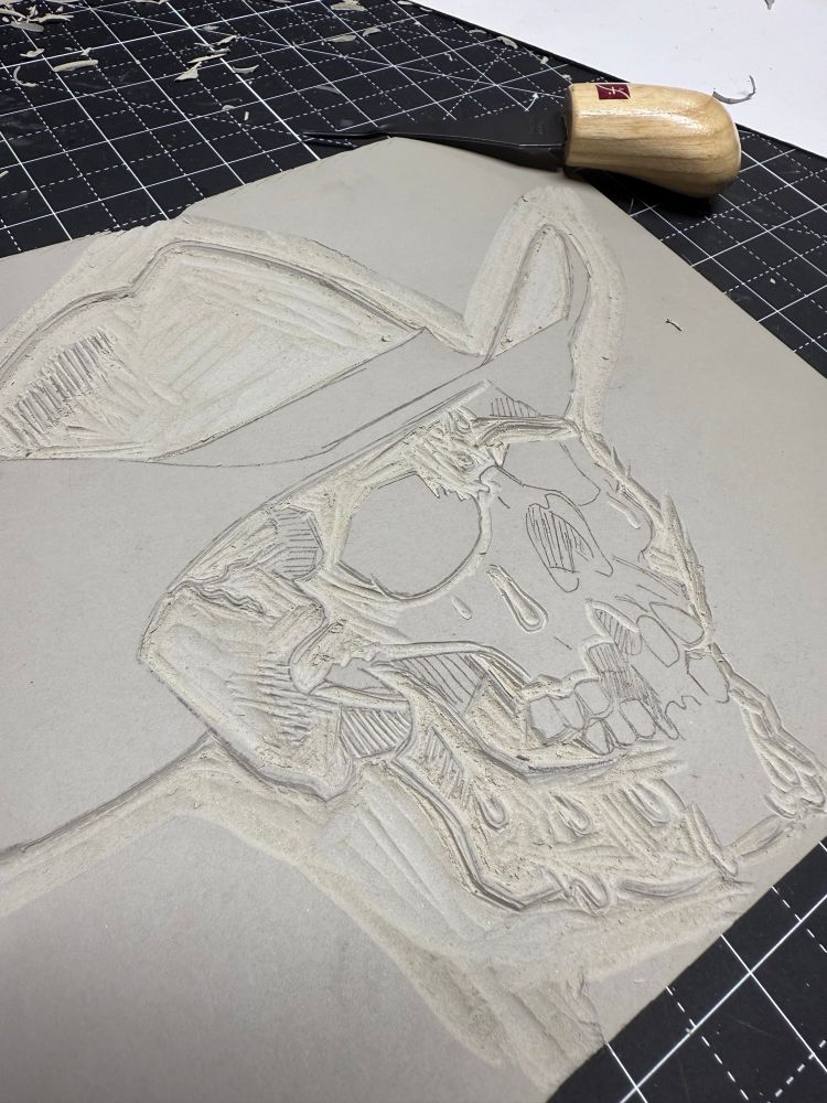 A linocut in progress of a sweaty skull cowboy  