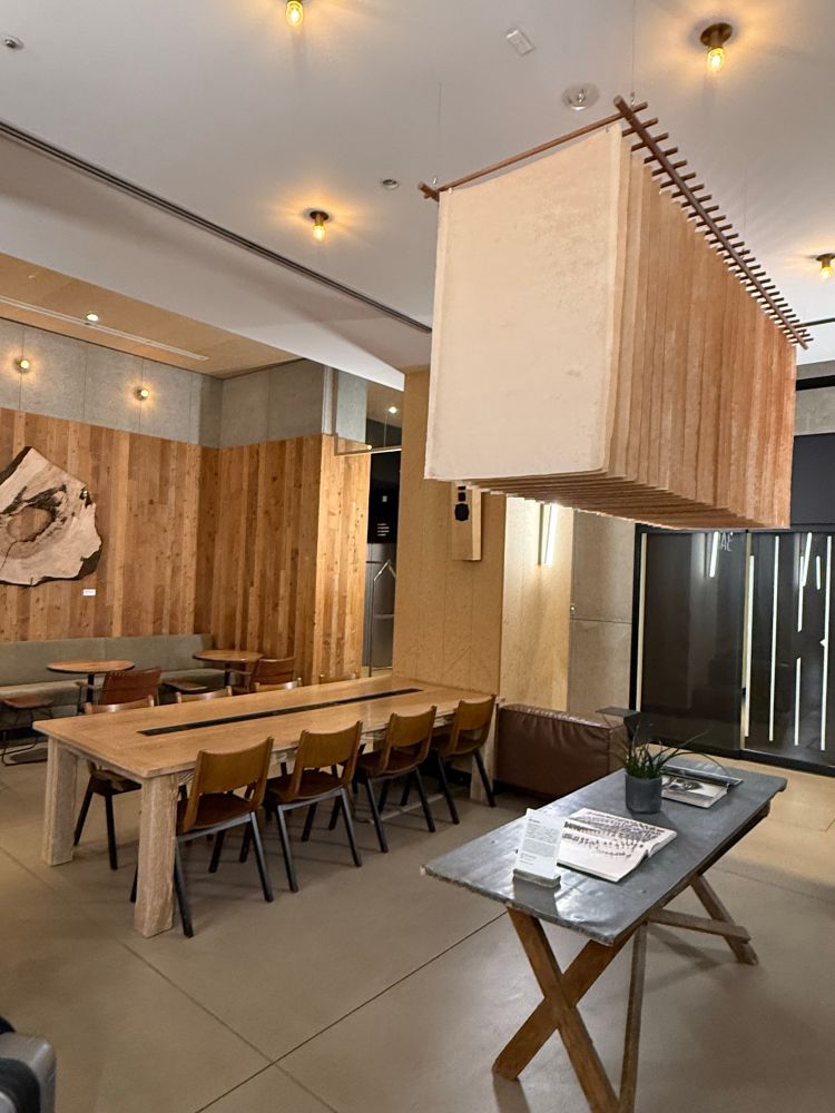 dimly lit hotel lobby area of a new-agey hotel in Tokyo. sheets of unbreached fabric hanging from the ceiling.