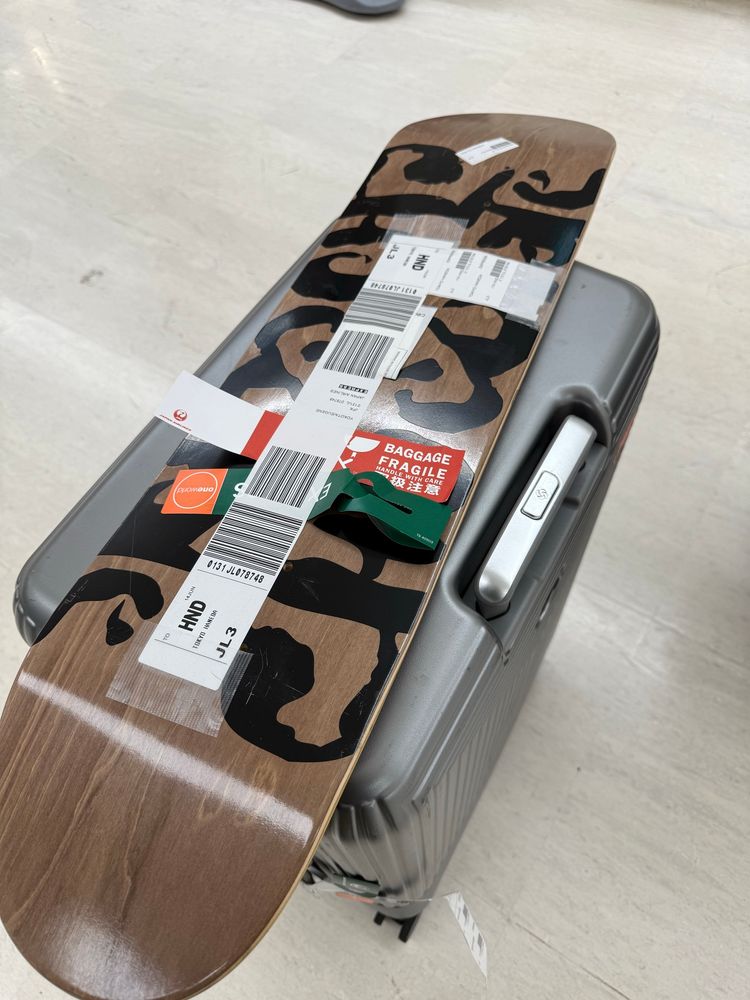 a skateboard deck with airline luggage tags on top a suitcase