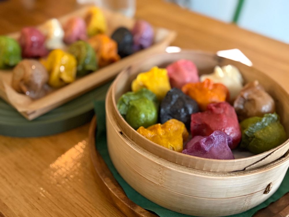 assortment of steamed and fried dumplings in different colors like green, yellow, and purple