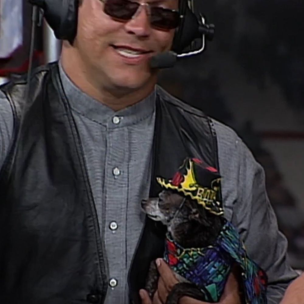 a close-up of mongo holding pepe, who has a very colorful patterned coat on and a colorful hat on, both are reminiscent of "macho man" randy savage's gear style and the hat has a batman logo and says BATMAN on the back