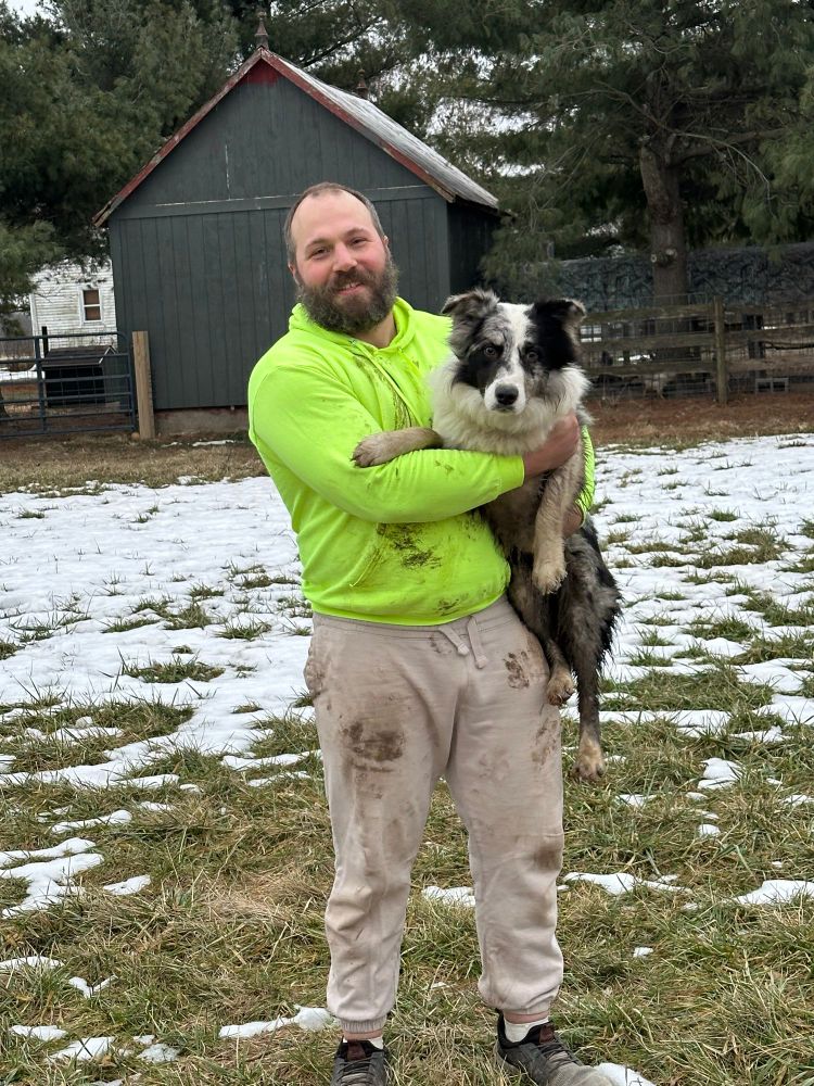 me covered in mud holding my dirty border collie Ullr in front of our chicken coop 