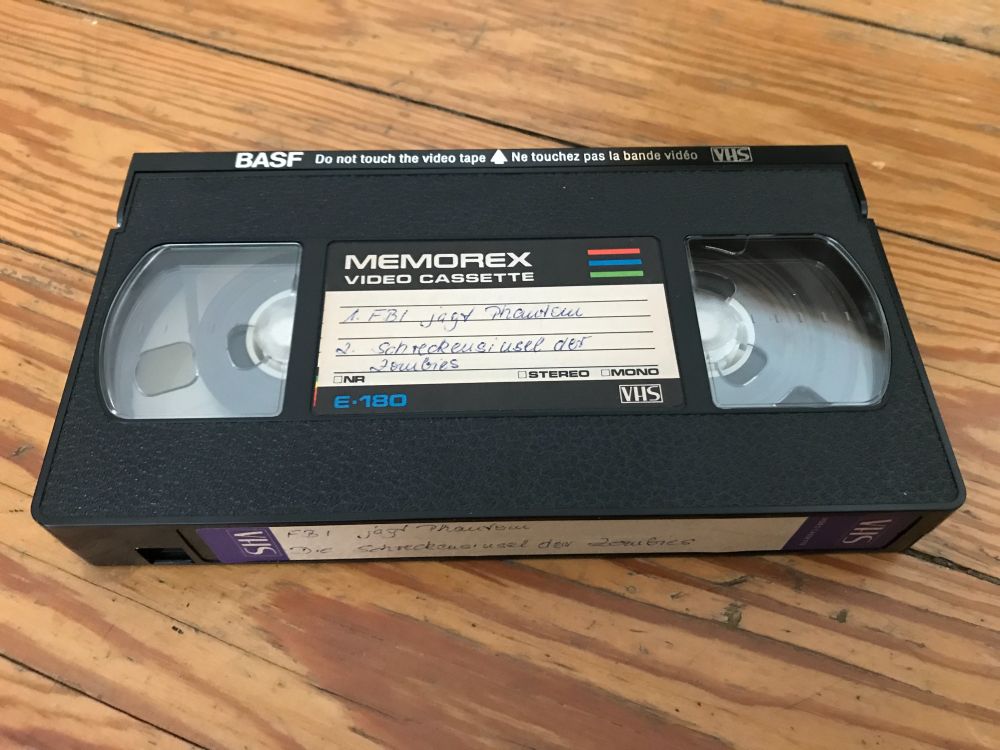 Eine alte Videocassette ohne Hülle mit handbeschriebenem Etikett:
1. FBI jagt Phantom
2. Großangriff der Zombies
