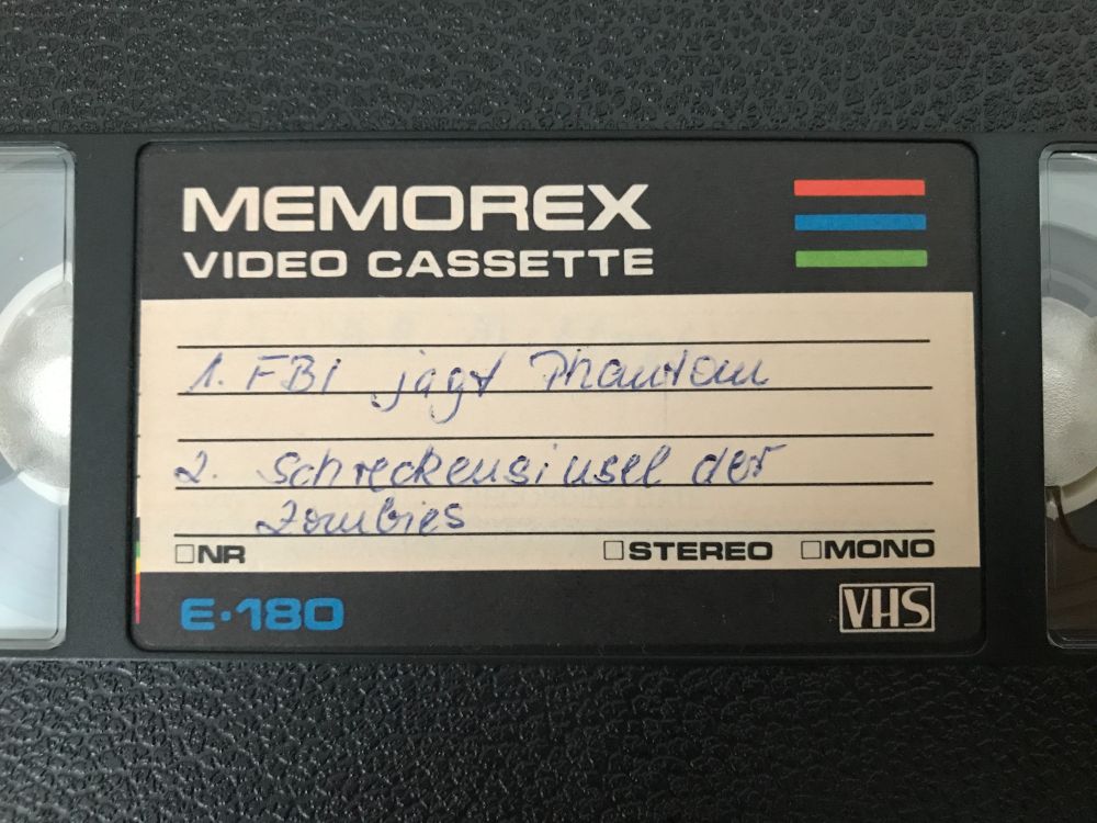 Eine alte Videocassette ohne Hülle mit handbeschriebenem Etikett:
1. FBI jagt Phantom
2. Großangriff der Zombies