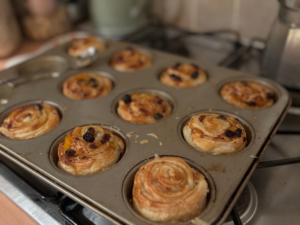 A metal baking tray with baked puff pastry cinnamon rolls fresh out of the oven.