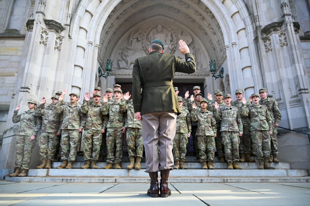ROTC cadets stand with their right hand in the air