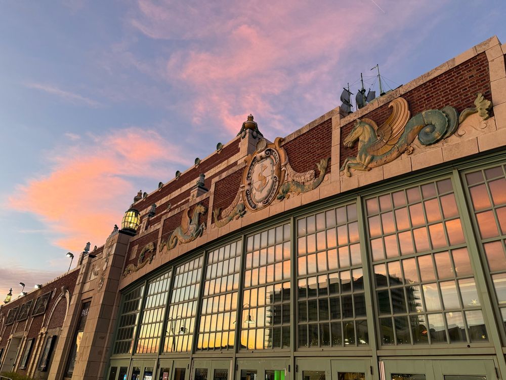 Convention Hall with pink clouds and blue sky behind it and reflected in its windows 