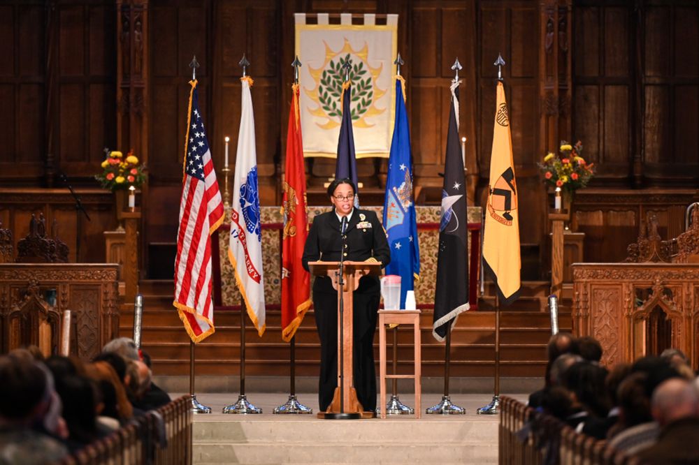 Captain Kelley T. Jones speaking at a podium with military and Princeton flags behind her