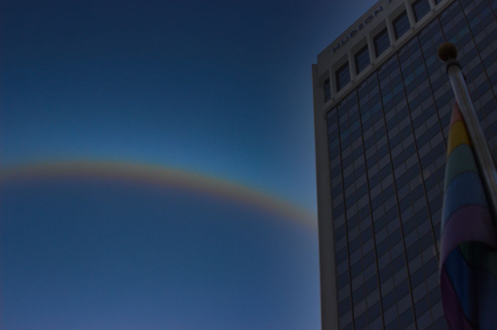 A rainbow in the background pride flag in the foreground